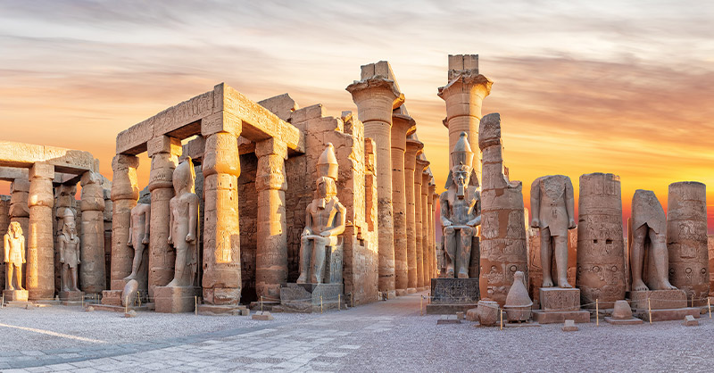 Image affichant le temple  de Karnak, avec des statues géantes et colonnes.