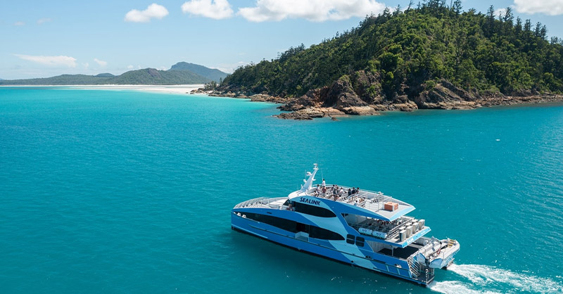 Image montrant un bateau de croisière sur la mer turquoise de Whitehaven Beach avec la plage et sable blanc.