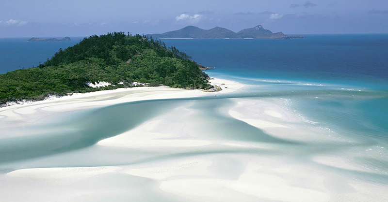 Image affichant une plage avec ses sables blancs, la mer turquoise, représentant Whitehaven Beach.